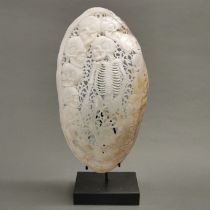 A hand carved river mussel mother of pearl shell with skeleton and skulls, polished; intricately