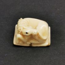 A carved fossilised mammoth tusk signed Netsuke of a horse.
