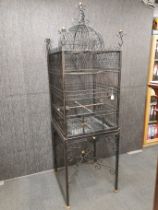 A very interesting dome topped wrought iron bird cage on stand with removable bottom shelf for