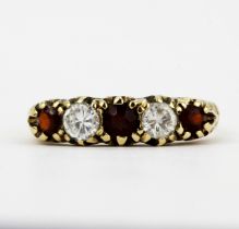 A hallmarked 9ct yellow gold ring set with garnets and white stones, (N).