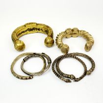 Two hammered brass slave bangles, largest W. 9cm. Together with a group of four handmade white metal