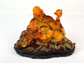 An amber coloured resin figure of the seated happy Buddha, H. 12cm.