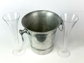 A vintage aluminium ice bucket with a pair of cut decorated champagne flutes.