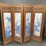 A four section Chinese carved hardwood screen with blue and white decorated porcelain panels, H.