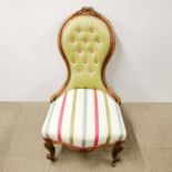 A carved and re-upholstered balloon back nursing chair on castors, H. 95cm.