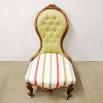 A carved and re-upholstered balloon back nursing chair on castors, H. 95cm.