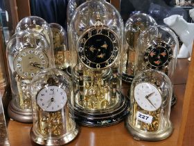 A group of five torsion anniversary clocks, three with glass domes, tallest 31cm.