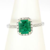 An 18ct white gold ring set with an emerald cut emerald and diamonds with diamond set shoulders, (