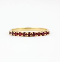 An 18ct yellow gold ruby set half eternity ring, (P).