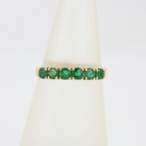 A 14ct yellow gold emerald set half eternity ring, (M).