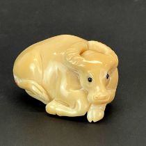 A carved Tagua nut water buffalo with inlaid bone signature, H. 3.5cm, L. 4.5cm.