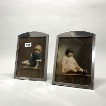 A pair of wooden backed hallmarked silver photograph frames containing hand tinted photographs of