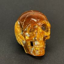 A hand carved amber human skull, H. 3cm. The amber originates from Indonesia, and dating from the