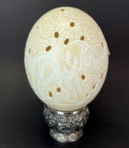A hand carved ostrich egg, engraved and pierced work depicting two elephants on either side, with
