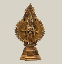 A gilt bronze figure of a standing multi head and multi arm deity with shrine, H. 41cm.