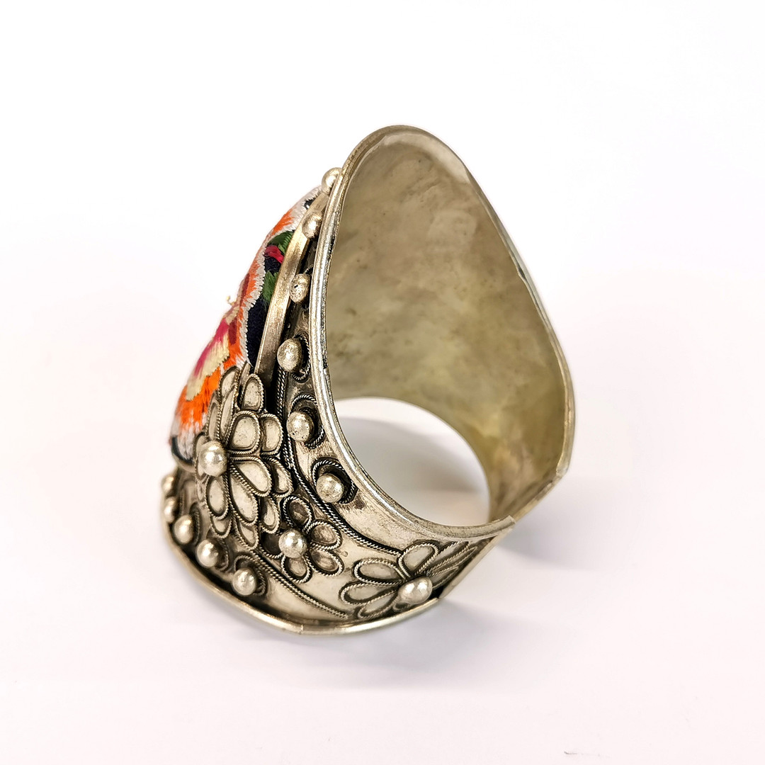 A Chinese white metal bangle inset with tribal embroidered fabric, top W. 9cm. - Bild 2 aus 3