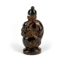 A Chinese carved cattle horn snuff bottle of a young dragon sitting on top of a ball, H, 8cm.