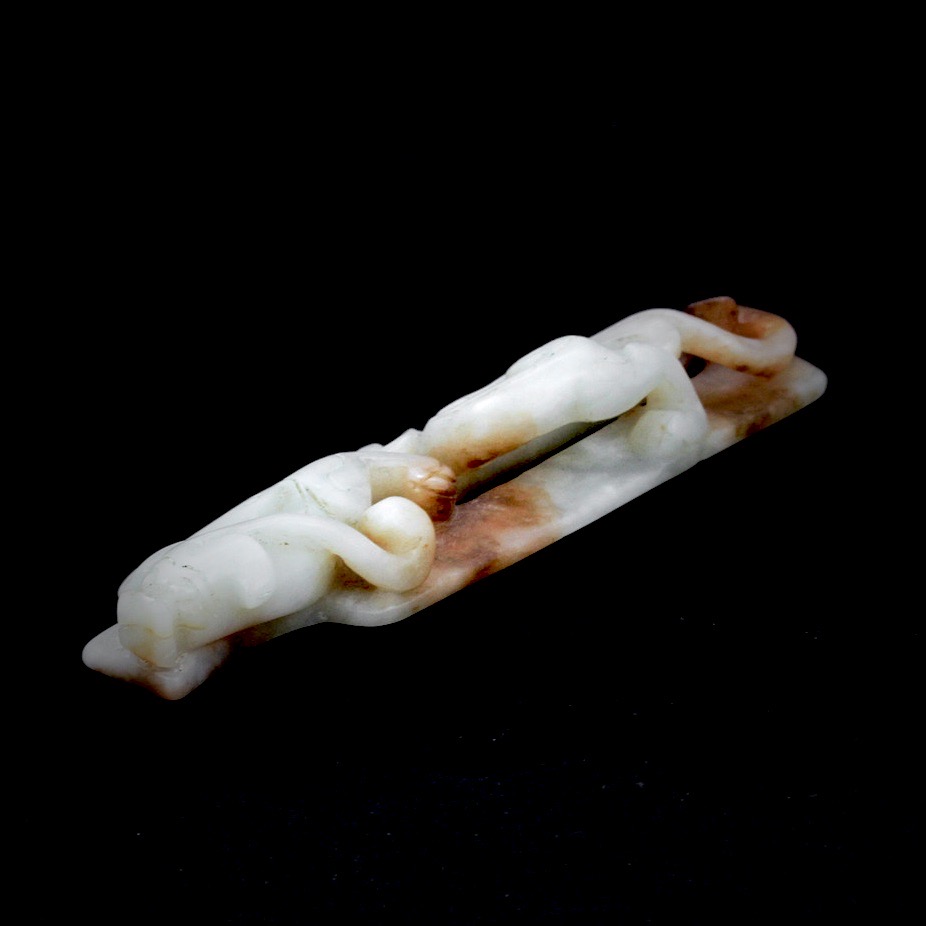 A Chinese celadon and russet jade amulet with dragon decoration, L. 13.4cm.