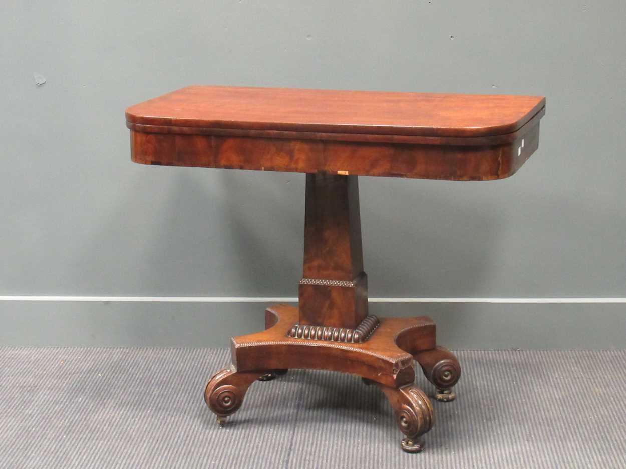 A Regency mahogany fold over tea table, the rounded rectangular top on a tapered column raised on