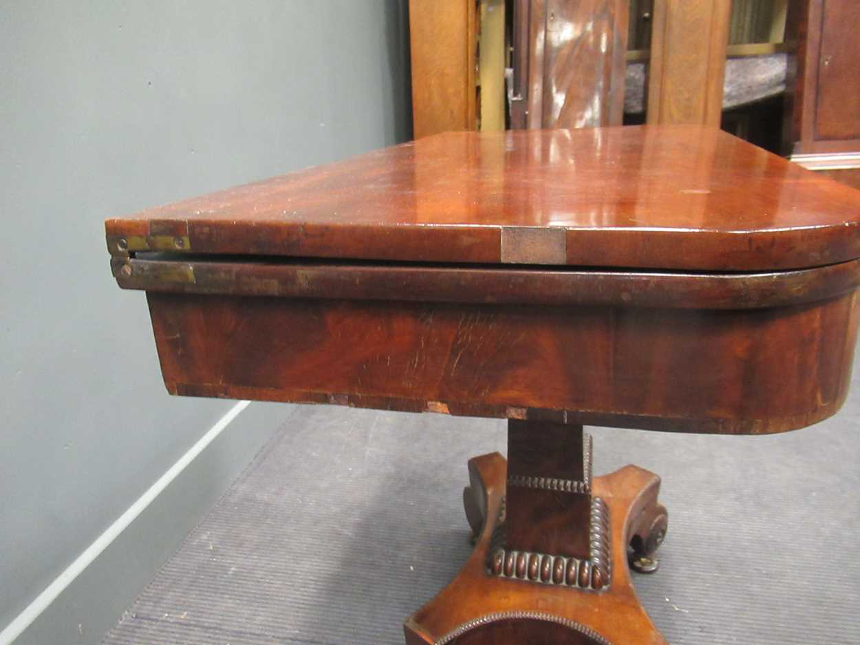 A Regency mahogany fold over tea table, the rounded rectangular top on a tapered column raised on - Image 4 of 9