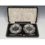 A pair of silver butter dishes with knives and glass liners, cased