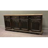 A French black-painted carved wood dresser base, comprising of four drawers over four cupboard doors