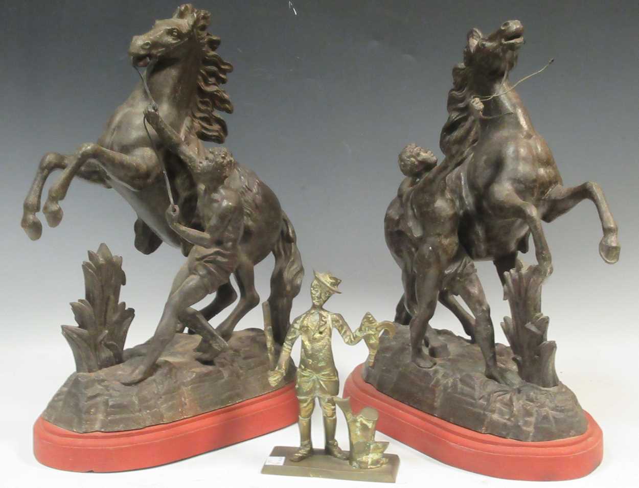 A pair Marley horses on red painted wooden plinths, 43 x 33 x 18cm; together with a brass figure