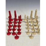 A box of turned bone chess piece, one side dyed red, and one natural