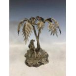 A silver plated table centrepiece in the form of a a greyhound by a tree fern on a shaped base circa