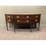 A 19th century Sheraton style mahogany sideboard, with bowed breakfront over a combination of