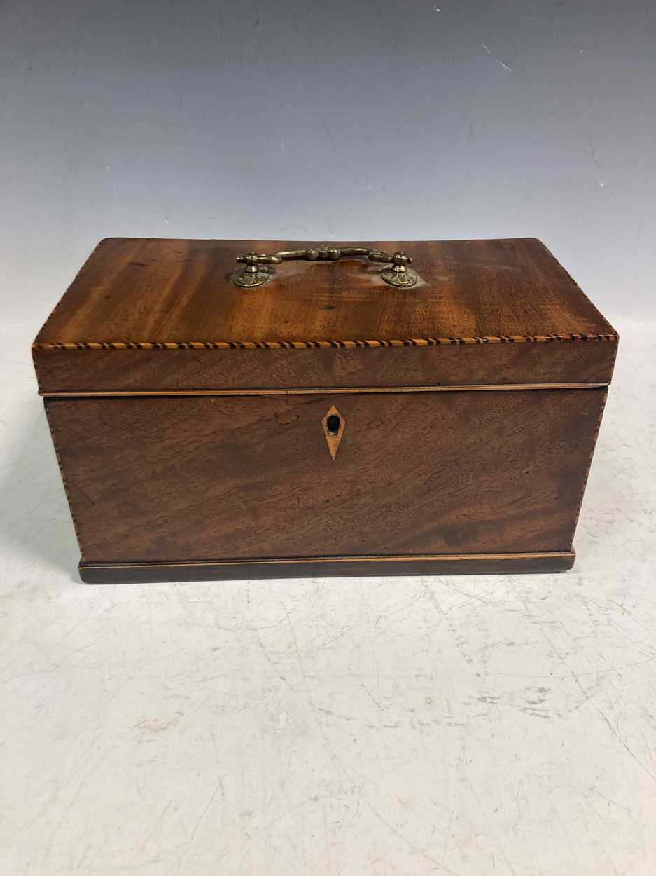 A George III mahogany tea caddy, the hinged lid with brass handle enclosing a three division