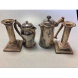 Two silver hot water jugs together with a pair of loaded silver candlesticks, 21.3ozt weighable