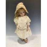 A Victorian style Bru bisque head doll by Gina Saunders 1988, on stand 61cm high