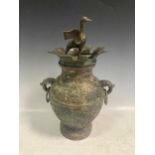 A Chinese bronze two-handled urn decorated with scrolling pattern and a Chinese duck finial to the