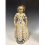 A 19th century wax shoulder head doll with inserted glass blue eyes, 52cm high on stand