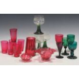 A collection of cranberry glass wine glasses and tall glasses; together with some green stemmed