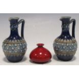 A pair of miniature Doulton Lambeth single handled jugs 9cm high, together with a small red glazed