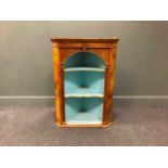 A George III style walnut corner cabinet, 20th century, with blue painted shelves within an arched