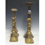 A pair of brass candlesticks, 31cm high, together with a larger brass candle stick and a carved wood
