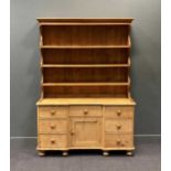 A late 19th/ early 20th century pine dresser, with boarded plate rack over an inverted breakfront