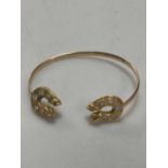 A diamond set hourseshoe torque bangle, horseshoes tested as 18ct gold, bangle tested as 9ct gold,