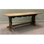 A 17th century style oak trestle table, the four plank cleated top raised on shaped end supports