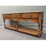 A three-drawer oak dresser with a scalloped apron on turned legs, 77 x 183.5 x 46.5cm