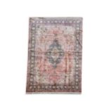 A Persian silk rug, the central medallion surrounded by flowers and leaves on a salmon ground with