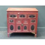 A Chinese red and black painted cabinet with an arrangement of five drawers around a pair of