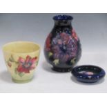 A Moorcroft vase 19cm high, ash tray 11.5cm diameter and green ground vase 11.5cm high (3)