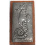 An embossed metal sheet with seahorse relief signed indistinctly lower right 18 x 10cm, mounted to a