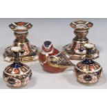 Royal Crown Derby - pair of small squat vases, pair of shaped candlesticks and a bird paperweight,