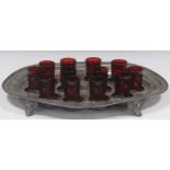 A pewter shot holder tray with twelve red glasses