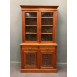 A late Victorian walnut glazed top bookcase, the base with carved cupboard doors below two short